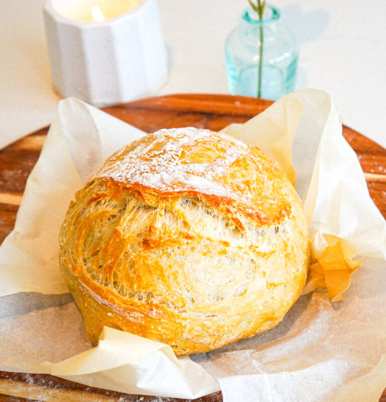 freshly baked homemade no-knead artisan bread on parchment and a cutting board