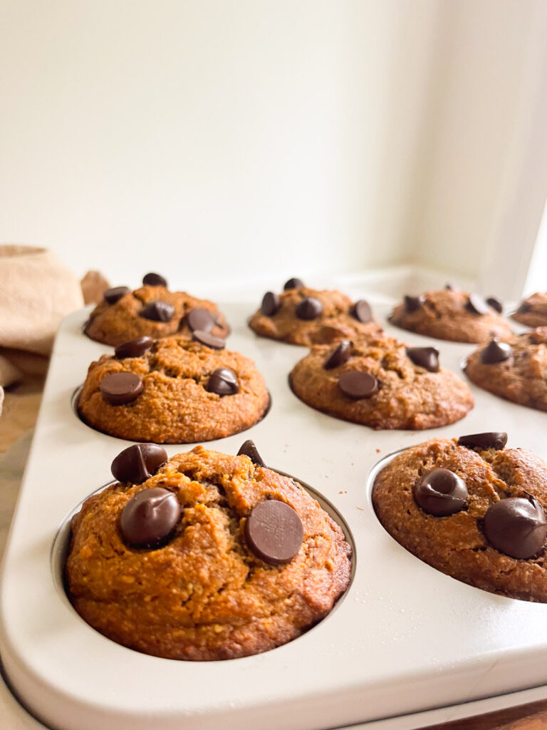 muffin tin with baked healthy dark chocolate chunk muffins