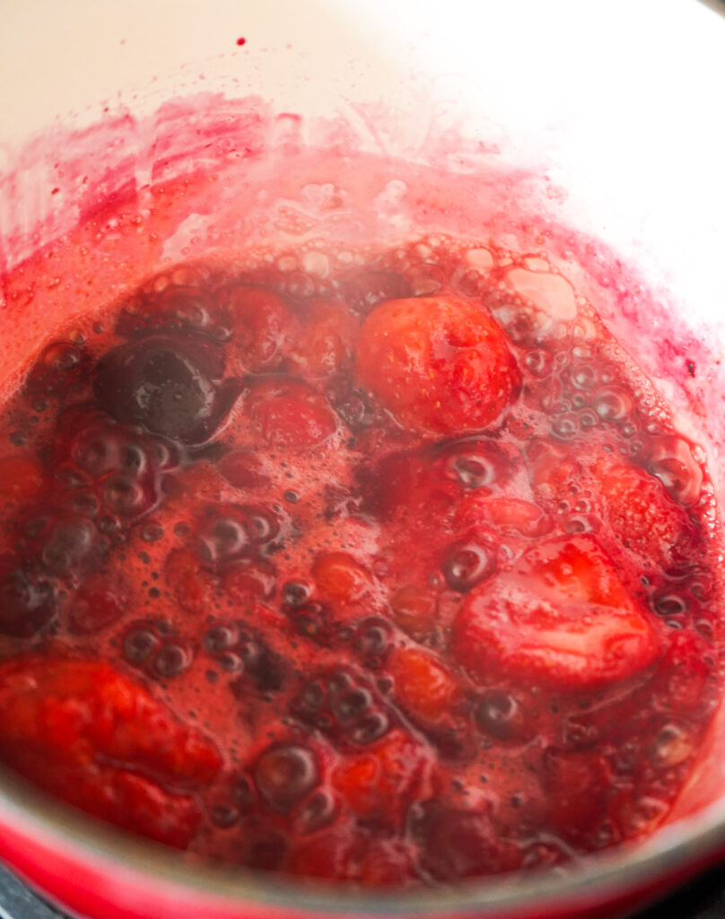 Mixed berries simmering in a sauce pot to make warm berry mixture for oatmeal.