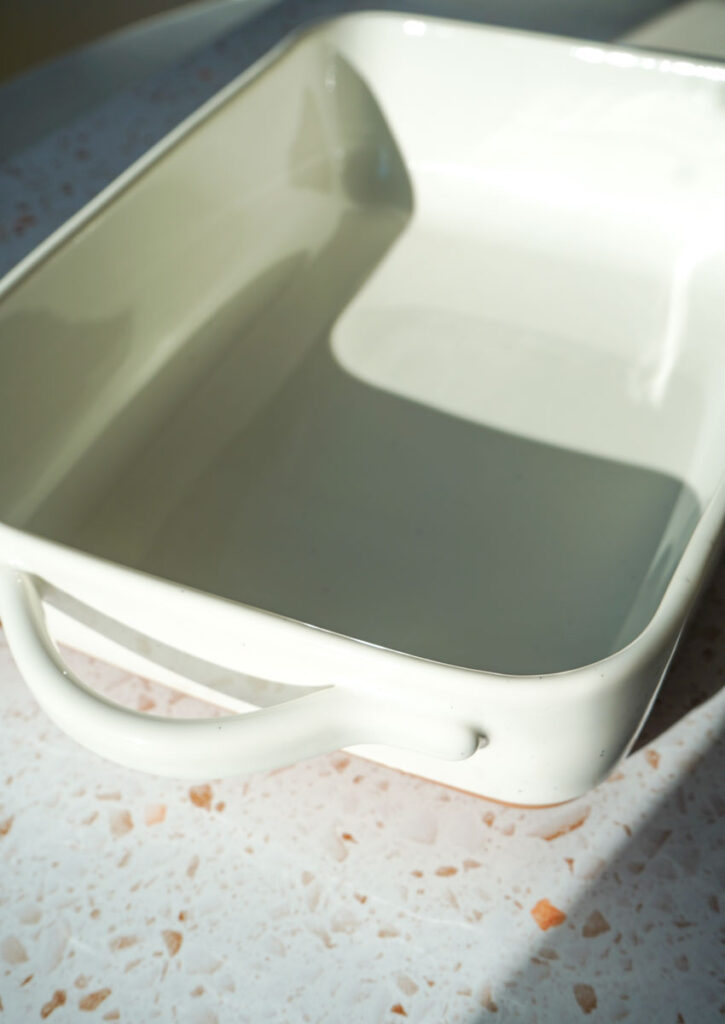 white ceramic baking dish in natural light on a white terrazzo counter