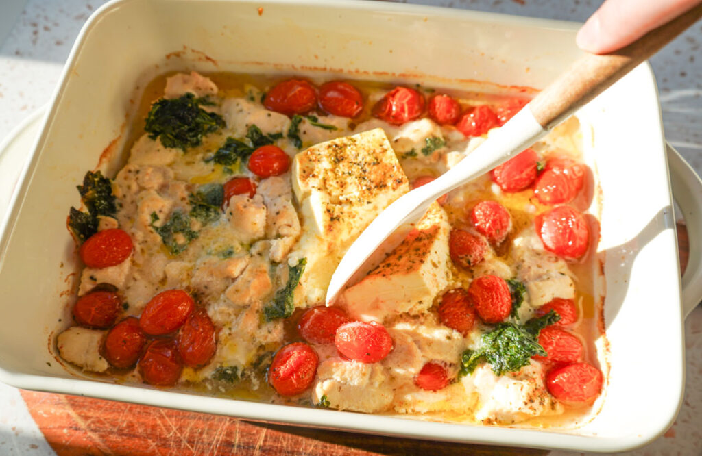 chicken, spinach, tomatoes and feta in a white casserole dish