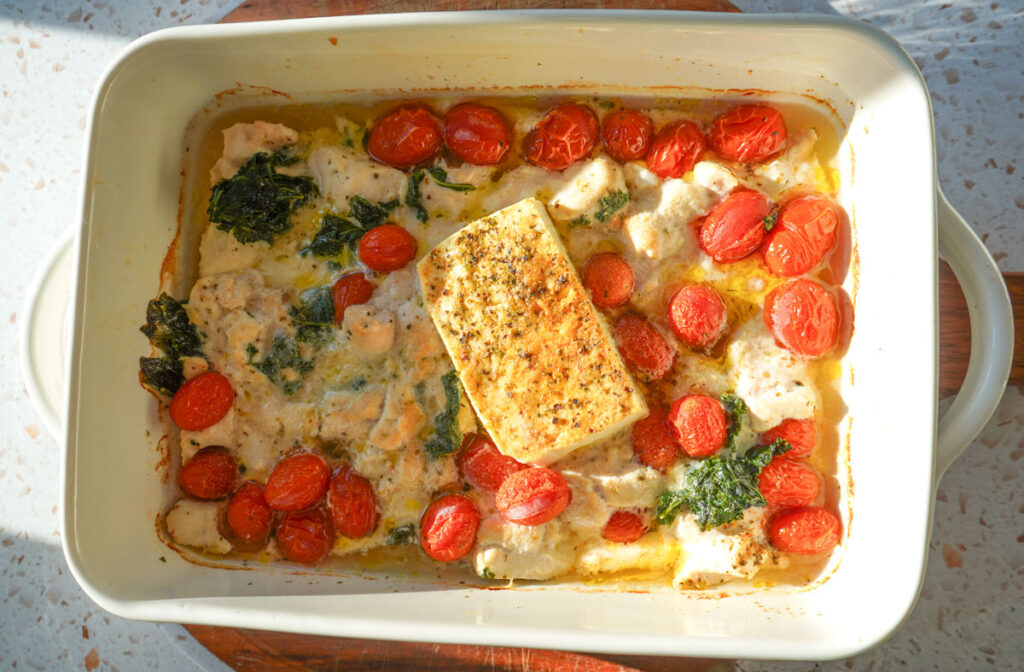 baked chicken tortellini with spinach tomatoes and feta in a white casserole dish