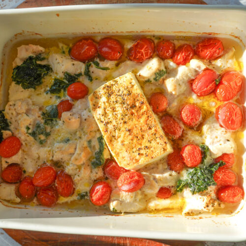 baked chicken tortellini with spinach tomatoes and feta in a white casserole dish