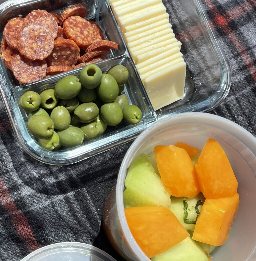 Honeydew cantaloupe melon salad packed in a container for a beach day alongside a charcuterie bento box
