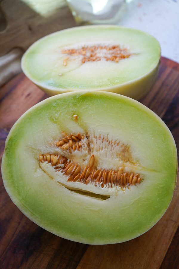 A honeydew melon sliced open on a cutting board