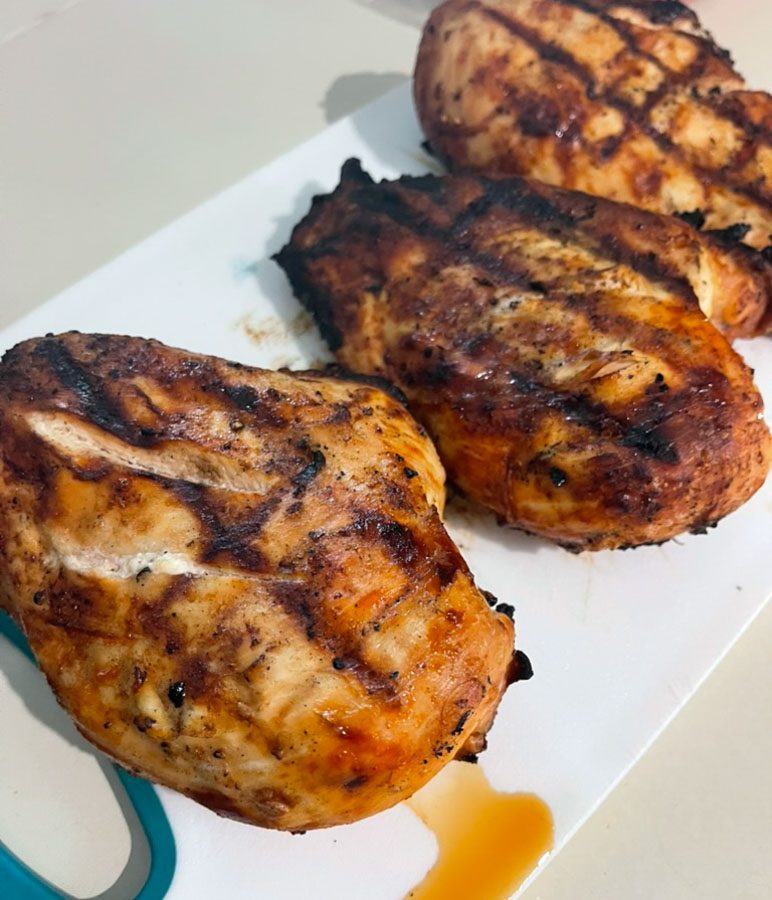 Grilled chicken breasts on a cutting board with grill marks from lime garlic smoked paprika marinade.