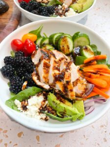 Blackberry grilled chicken salad with blackberry balsamic chili lime dressing in a white bowl