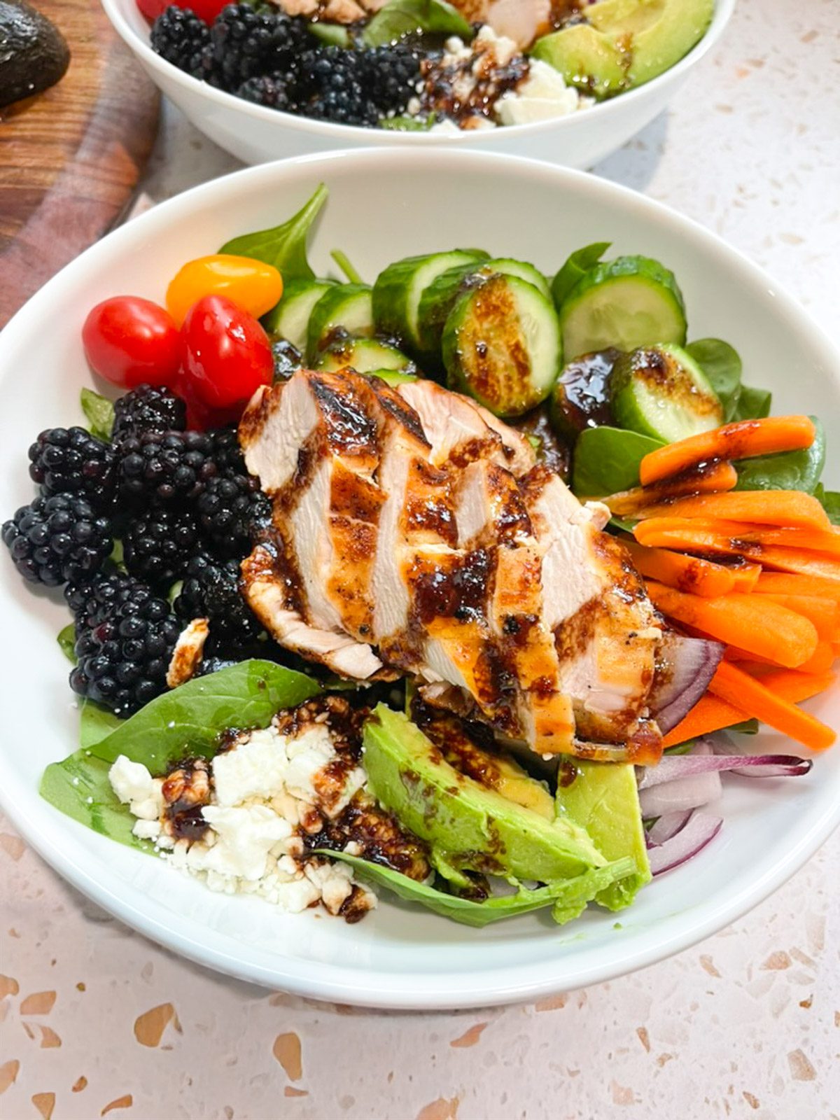 Blackberry grilled chicken salad with blackberry balsamic chili lime dressing in a white bowl