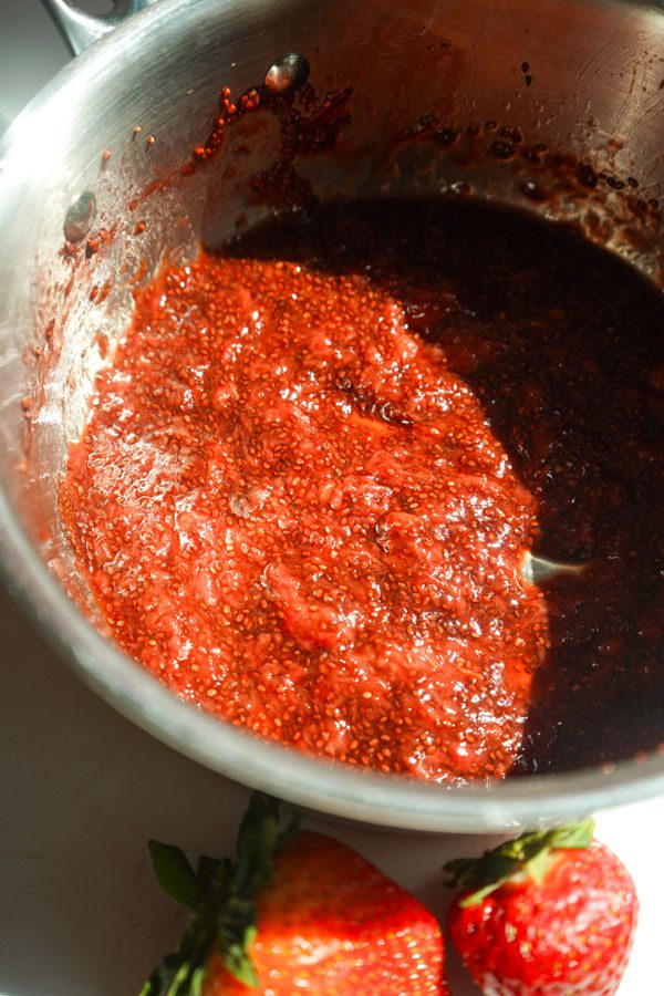 Homemade strawberry chia jam sweetened with honey close up shot in silver sauce pan.