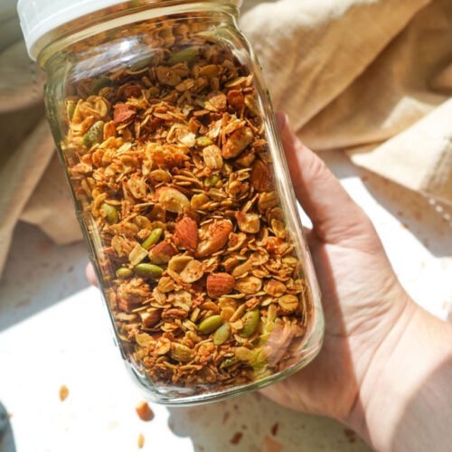 Glass jar filled with homemade honey roasted almond granola for meal prep and pantry storage.