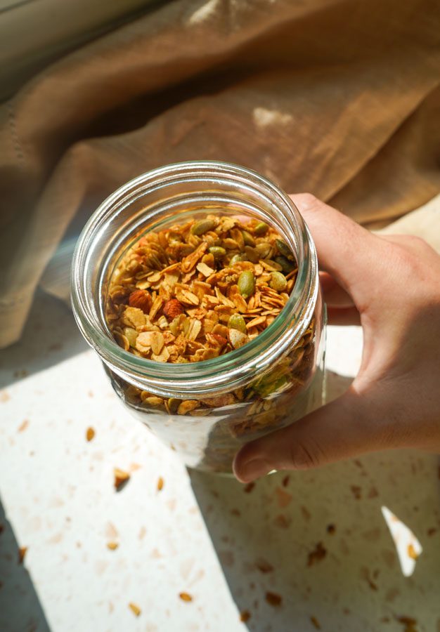 Glass jar filled with homemade honey roasted almond granola for meal prep and pantry storage.