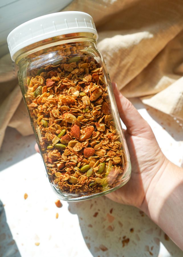 Glass jar filled with homemade honey roasted almond granola for meal prep and pantry storage.