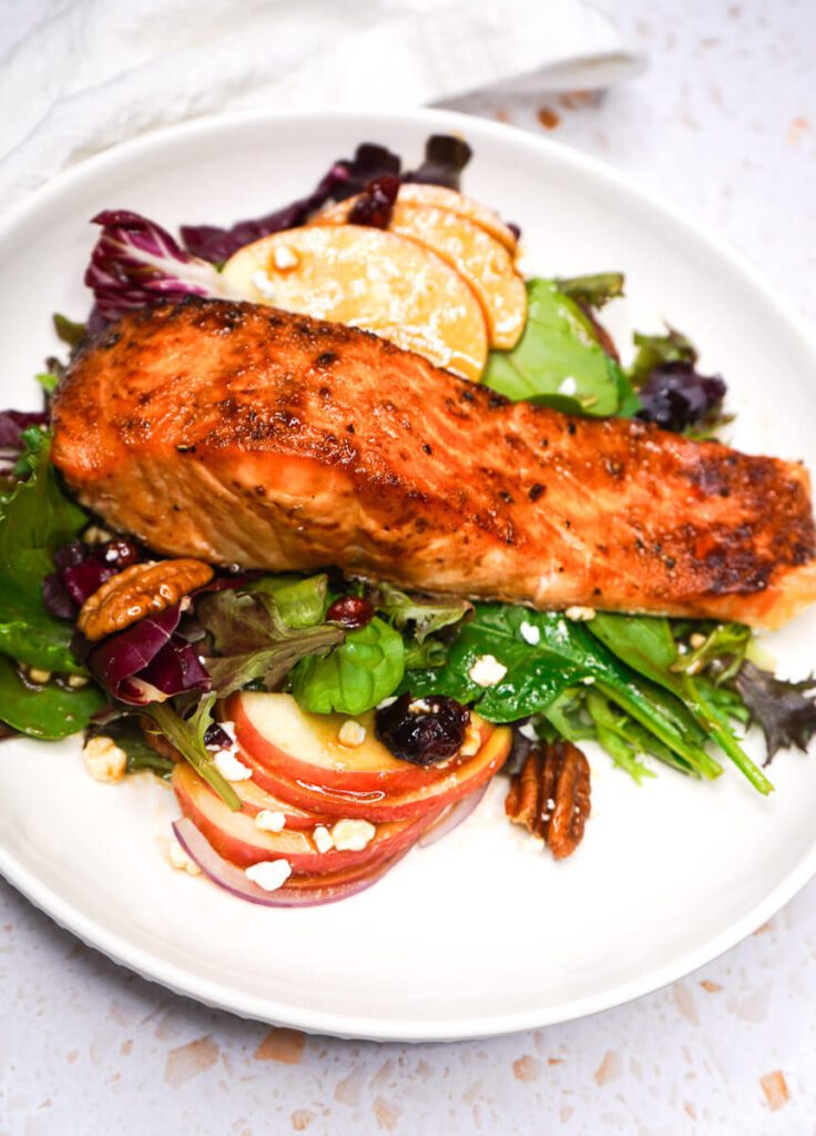 Air fryer maple balsamic salmon served directly over an apple pecan salad with crisp apples and toasted pecans.
