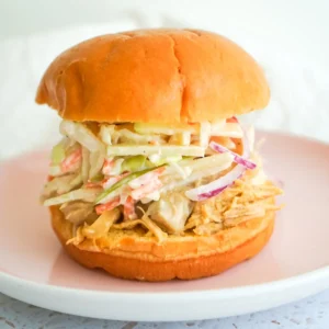 Juicy apple cider pulled chicken sandwich topped with creamy apple slaw on a brioche bun.