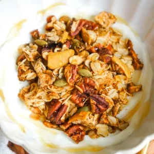 Overhead close-up shot of a creamy yogurt bowl topped with golden apple cinnamon pecan granola.