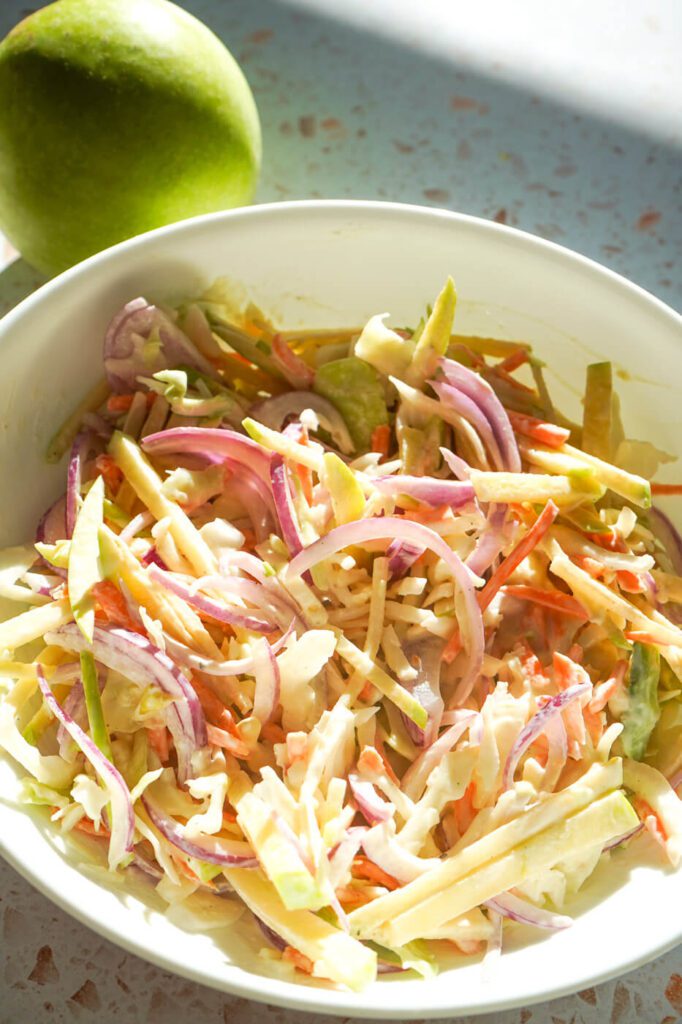 Creamy apple slaw made with coleslaw mix, Granny Smith apples, red onion, mayo, Greek yogurt, and Dijon mustard.